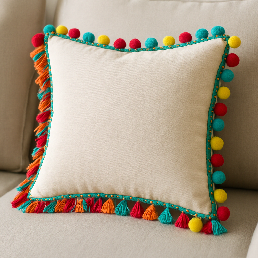 Fringe and pom‑pom accent pillow on a neutral sofa, showcasing a no‑sew trim upgrade along the edges—an inviting example of Room Decor Ideas DIY.